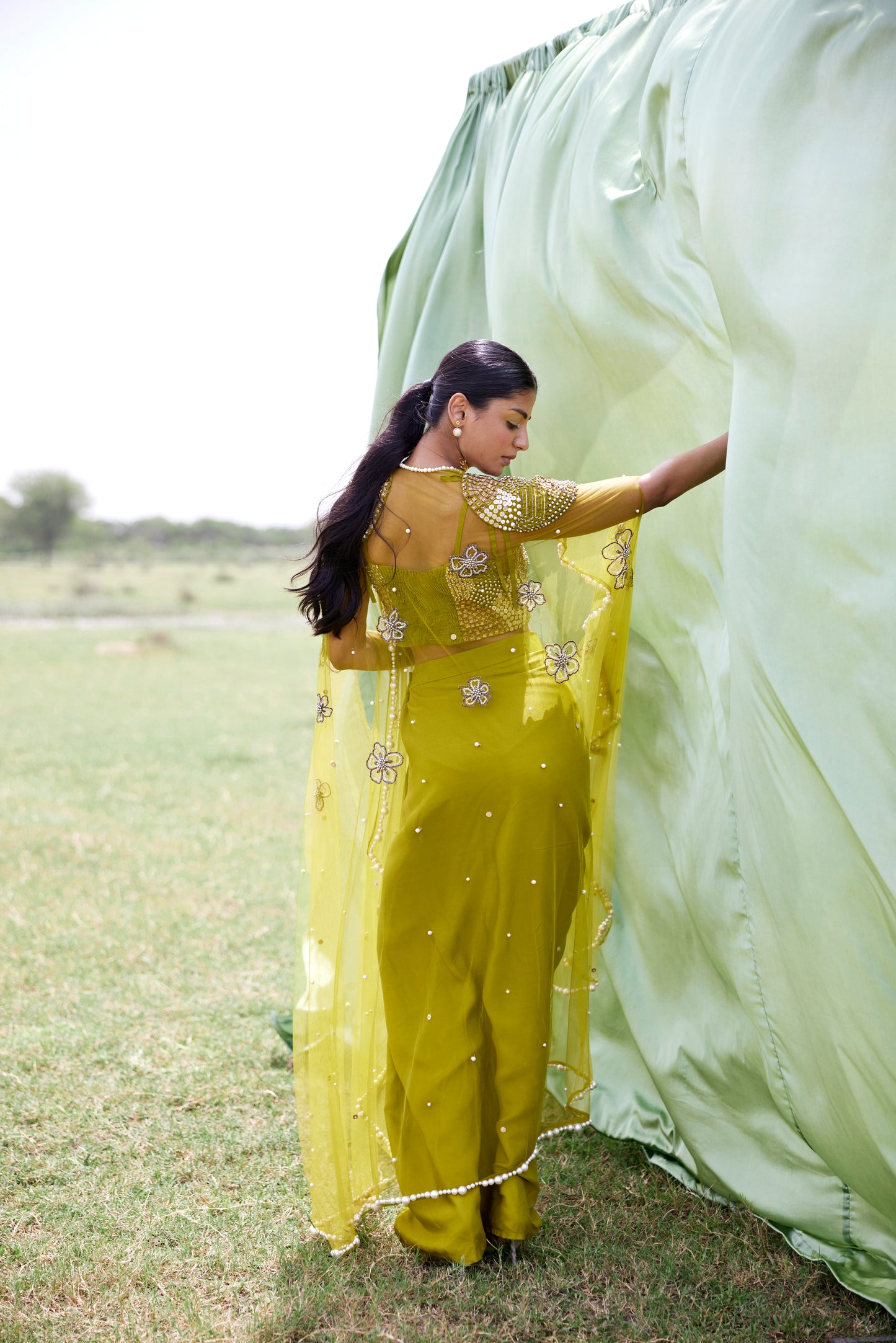 Satin green drape skirt paired with a chunky hand-embroidered blouse and a matching chunky embroidered cape in net for women